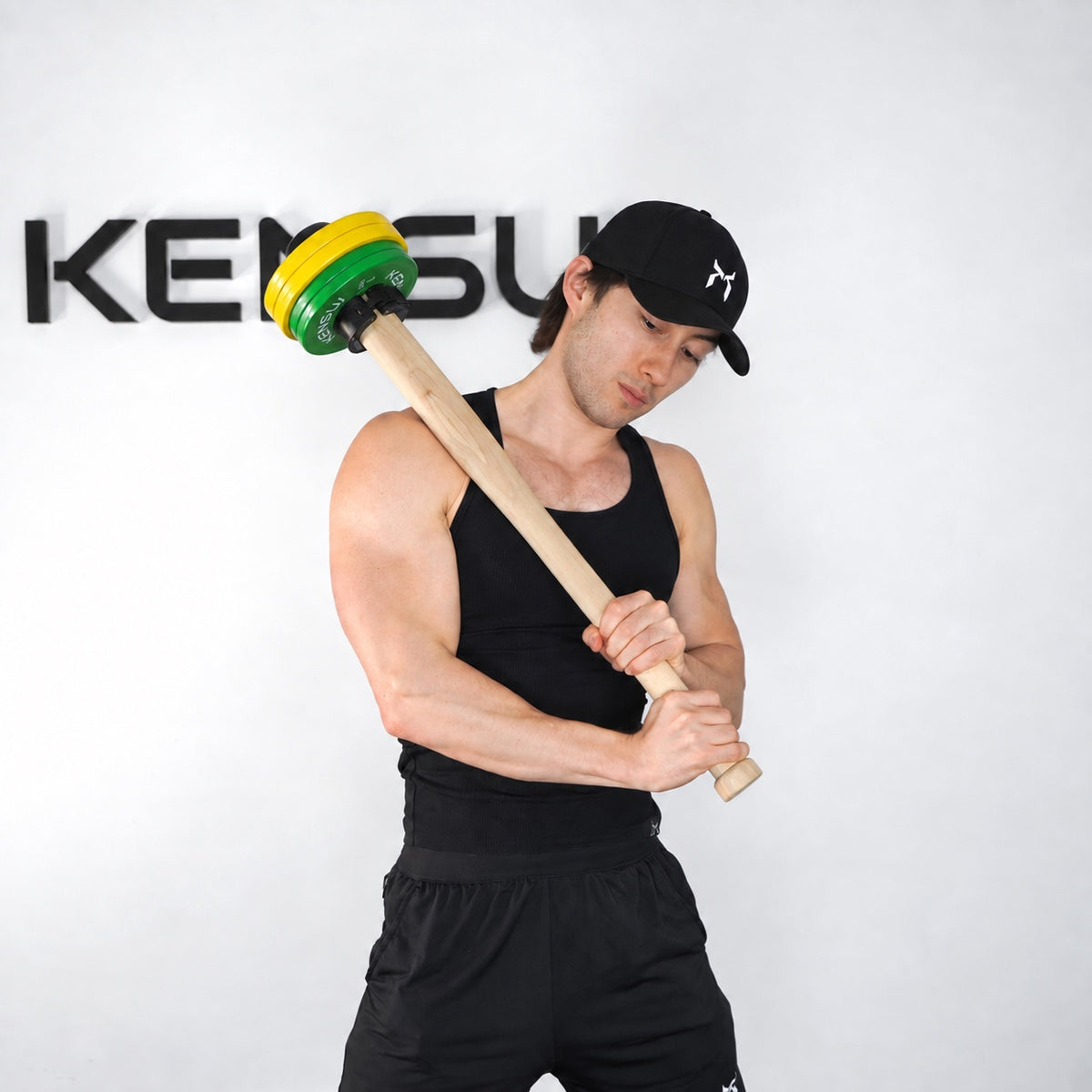 Athlete holding a wooden EZ-CLACE PRO diagonally with yellow and green weight plates.