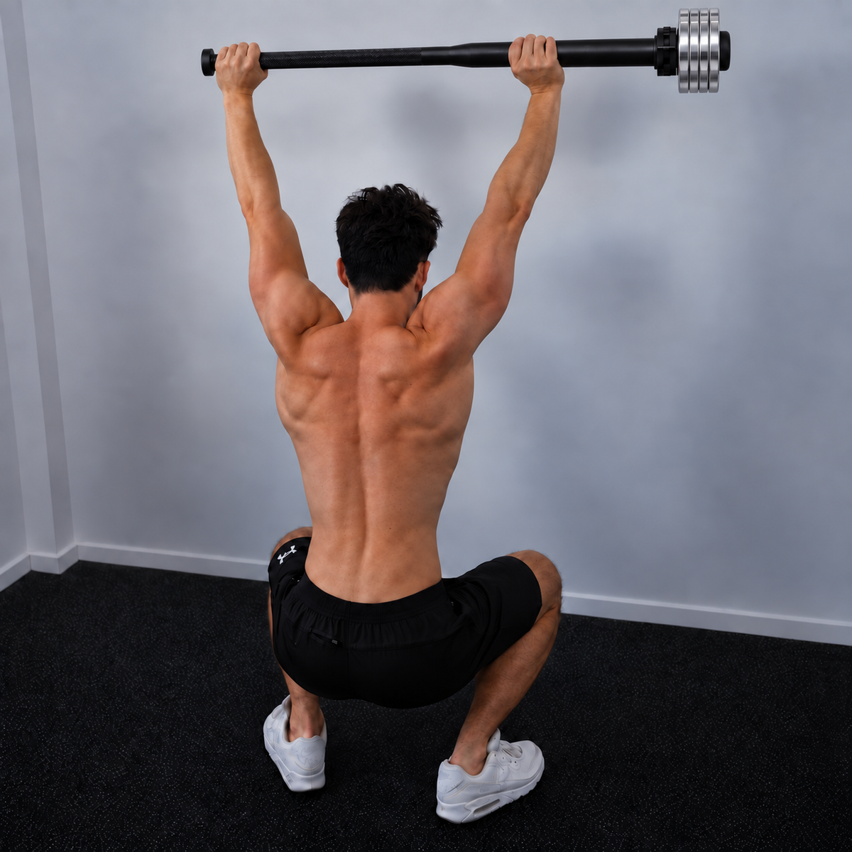 Rear view of an athlete performing an overhead squat with the black EZ-MACE MAX and four chrome VersaPlates Mini.