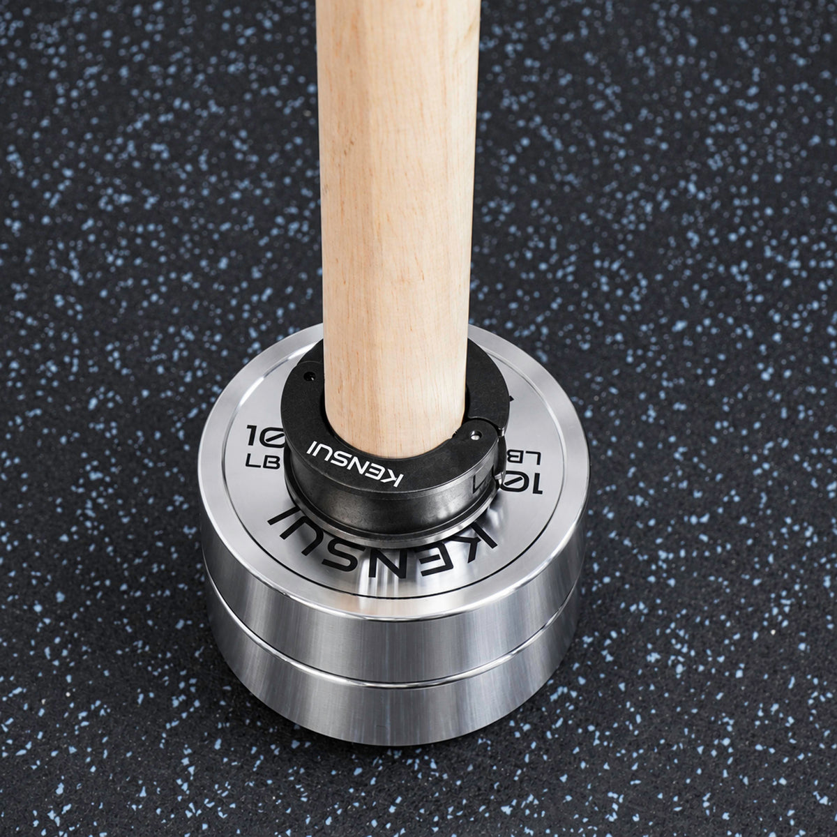 Close-up of the black Kensui collar securing chrome weight plates on the wooden loading sleeve.