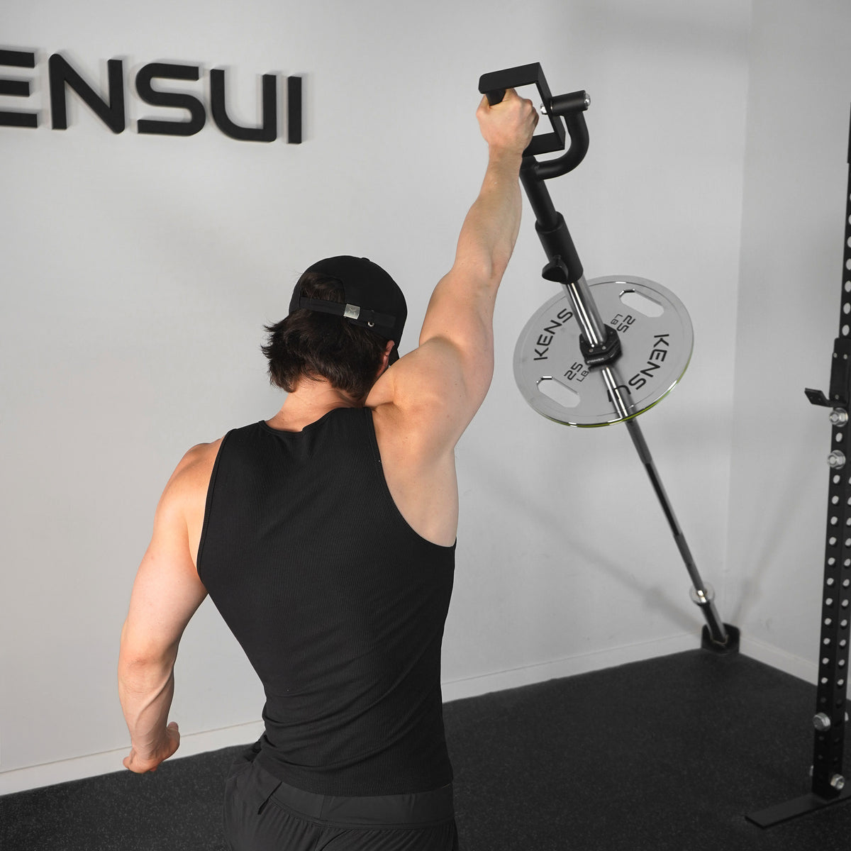 Athlete pressing the KENSUI rotating landmine attachment overhead with one arm extended.