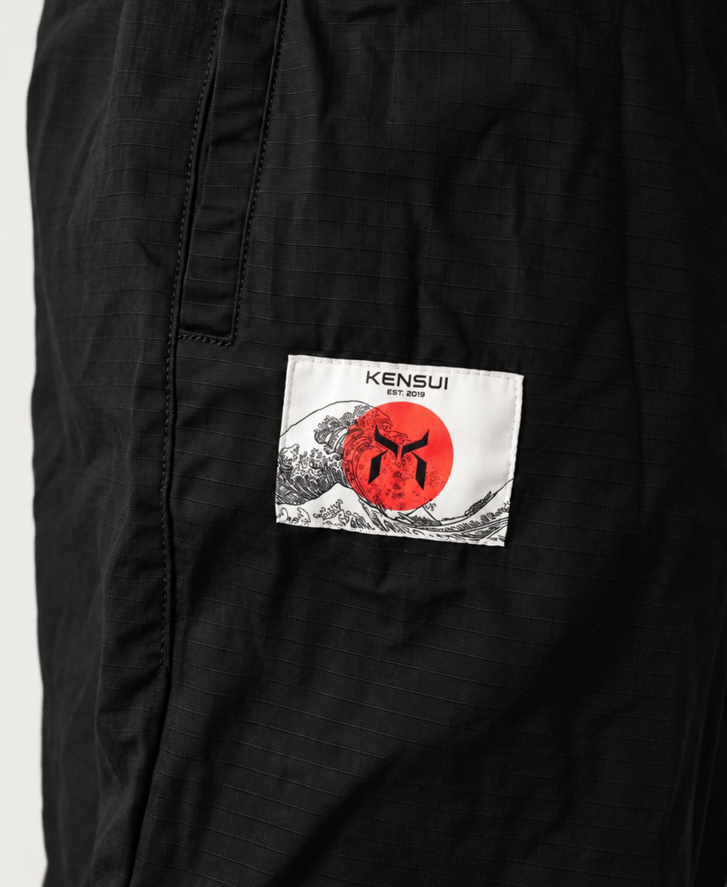 Close-up of the white and red Kensui patch on black cotton fabric.