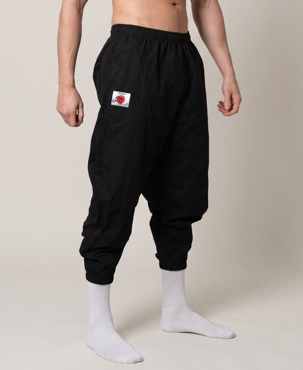 Black jogger modeled from the front, showing the relaxed leg and elastic ankle cuffs.