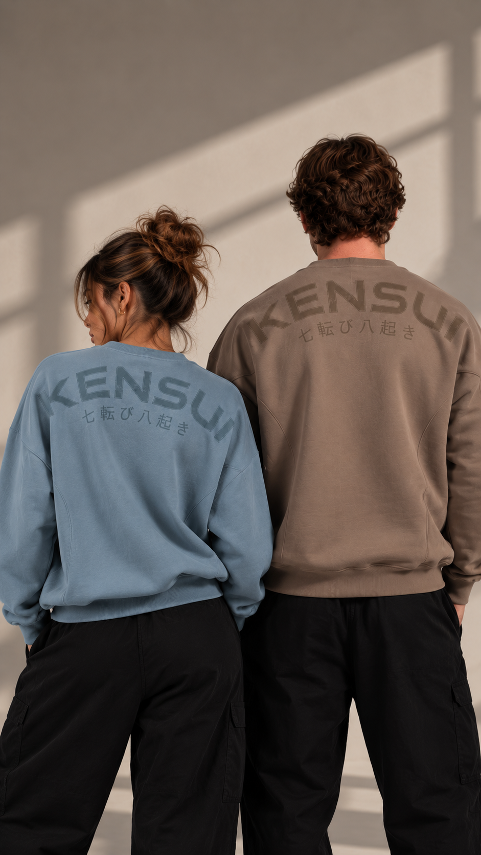 Two models wearing blue and taupe Nanakoribi Crew sweatshirts, showing the back prints.