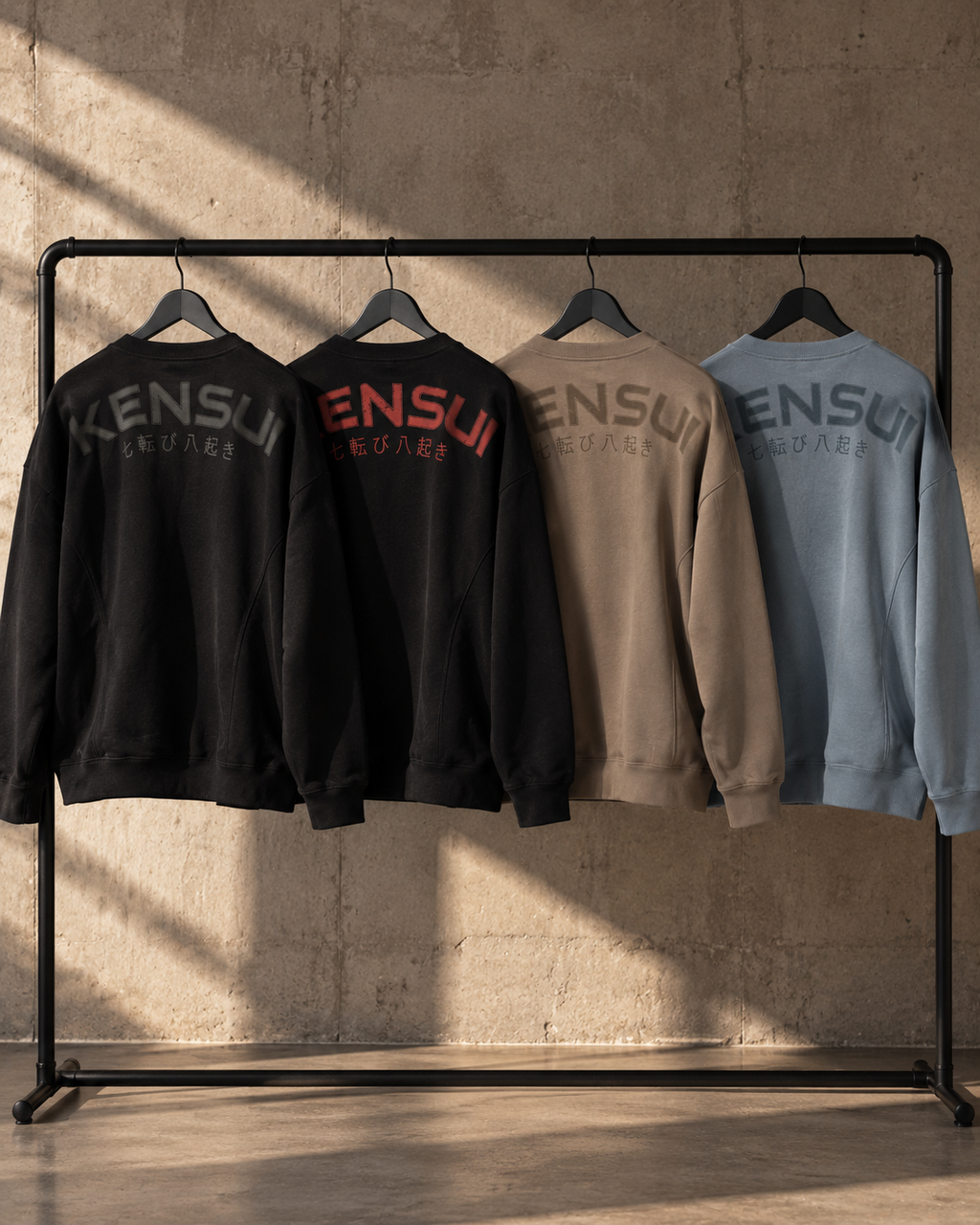 Nanakoribi Crew sweatshirts in Black, Black / Red, Taupe and Blue hanging on a clothing rail.