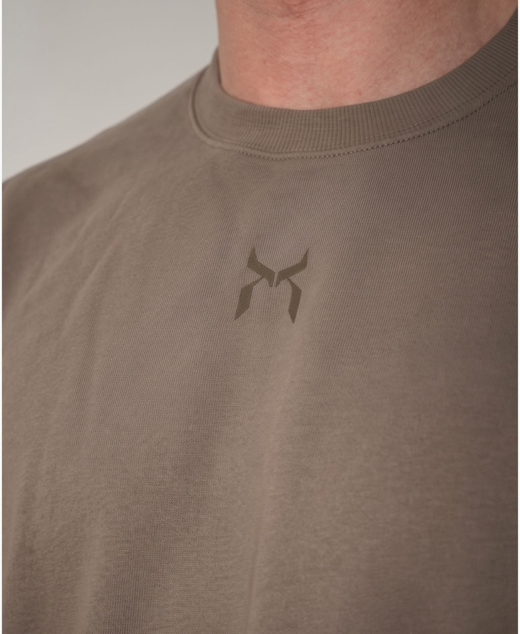 Nanakoribi Crew in taupe, close-up of the chest logo and ribbed neckline.