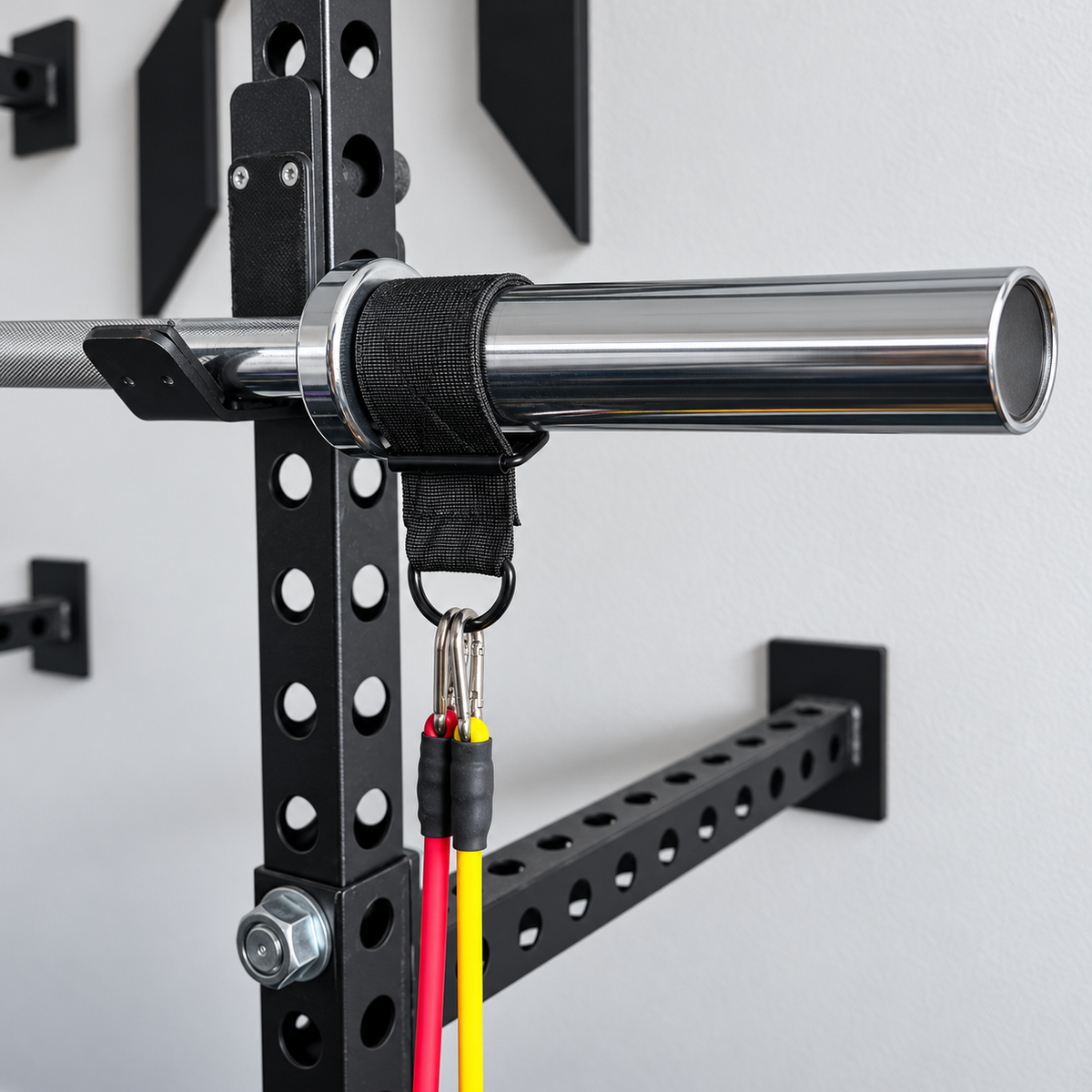 Rubber lined barbell strap connected to red and yellow resistance bands through carabiners