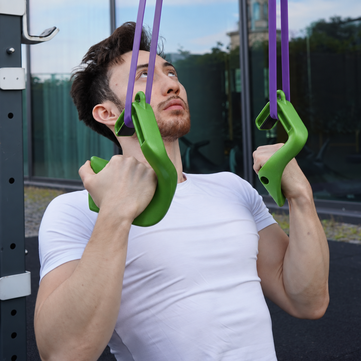 Athlete using green Swissies S V2 Max grips with purple resistance bands outdoors.