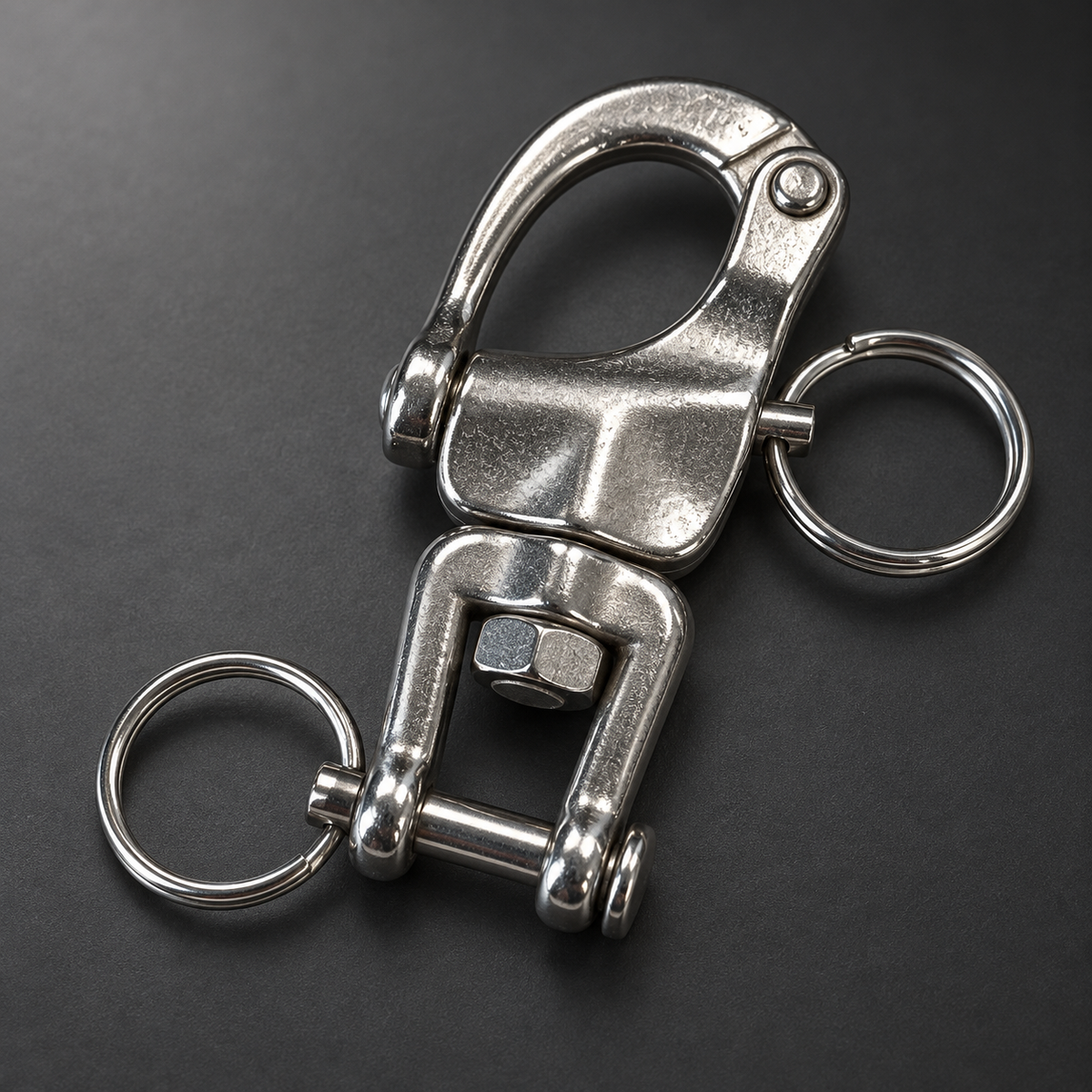 Close-up of the swivel shackle, release rings and removable cross-pin on a charcoal background.