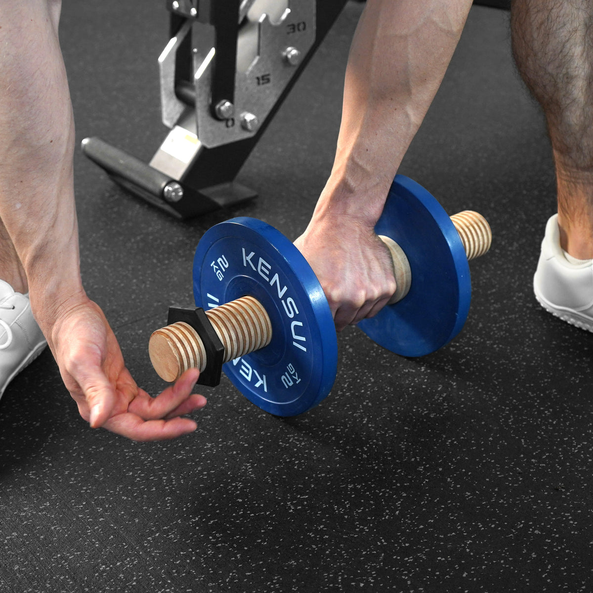 Adjusting the collar on a Timber wooden dumbbell loaded with blue plates