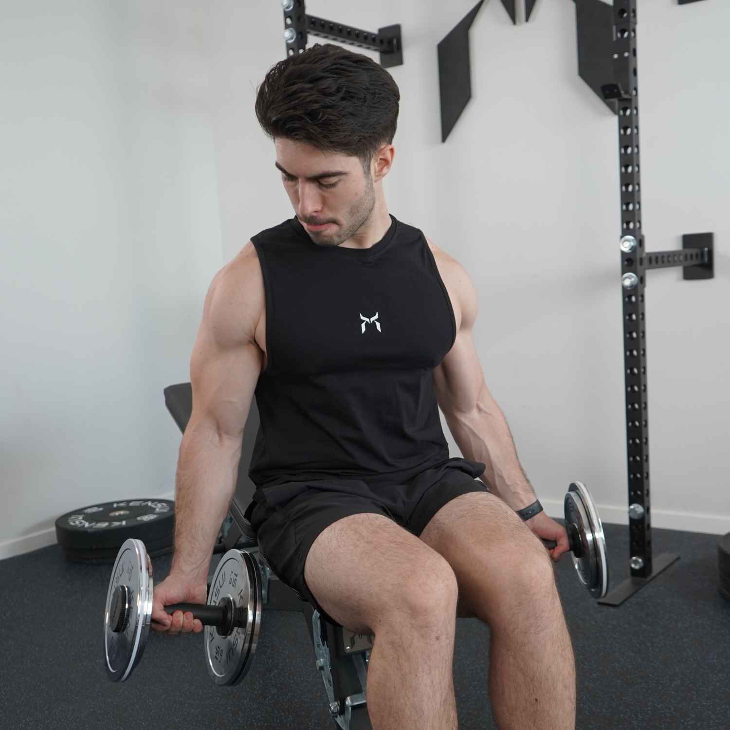 
Person seated on a bench holding dumbbells.
