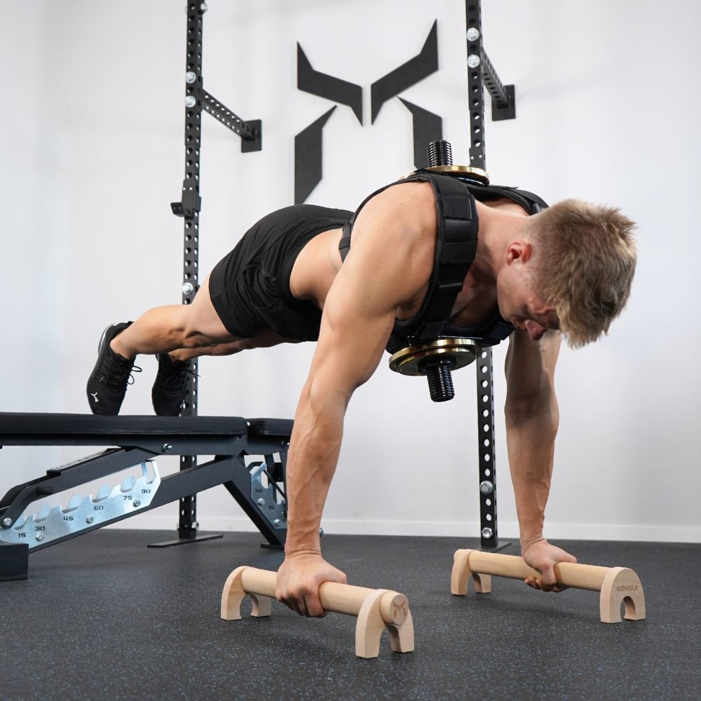 Person performing an elevated push-up on wooden parallettes wearing EZ-VEST.