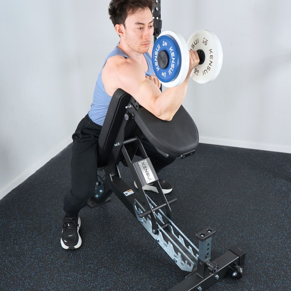 Man doing a preacher-style dumbbell curl with his upper arm supported on the raised bench backrest.