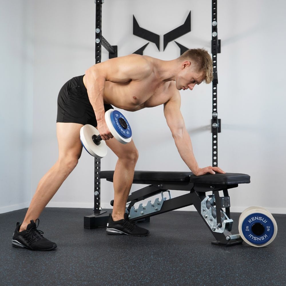 Man doing a one-arm dumbbell row with one hand supported on a flat bench.