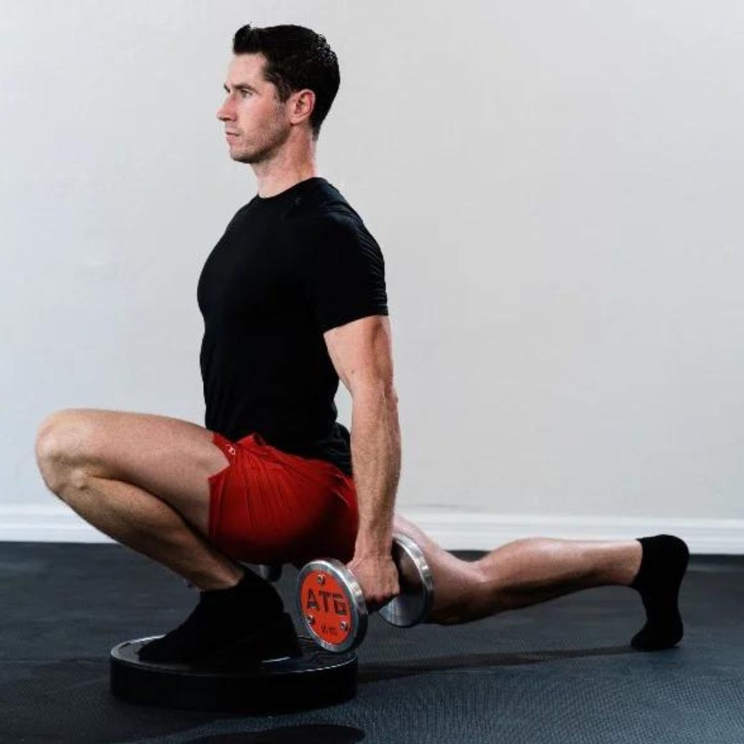 Person holding dumbbells in a deep split squat with front foot elevated.