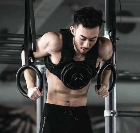 Person performing weighted dips on rings.