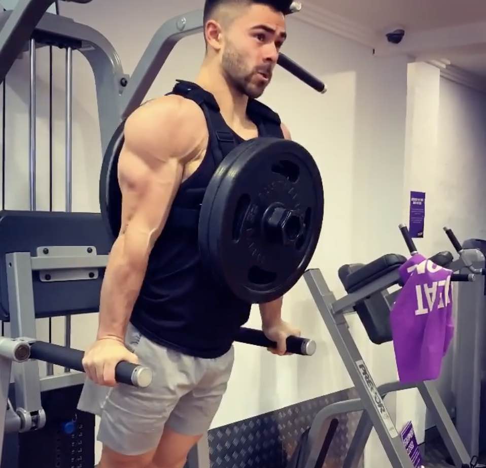 Person performing parallel-bar dips wearing a plate-loaded vest.