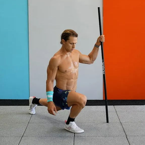 Person doing a split squat while holding a support pole.