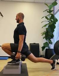 Person holding dumbbells in an elevated-front-foot split squat.